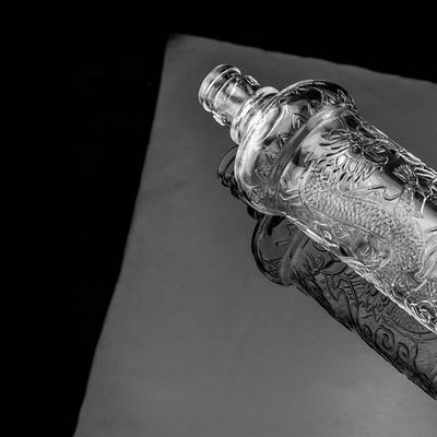 Hermosa botella de vidrio en relieve de dragón con tapa dorada logotipo personalizado y base de vidrio